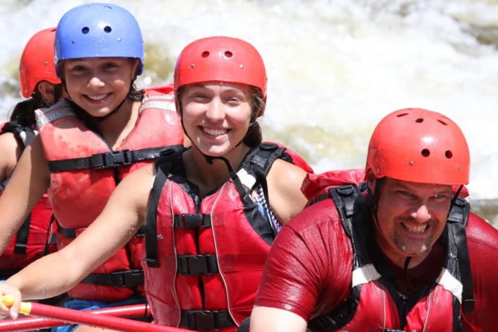Young rafters smiling while dad grimaces