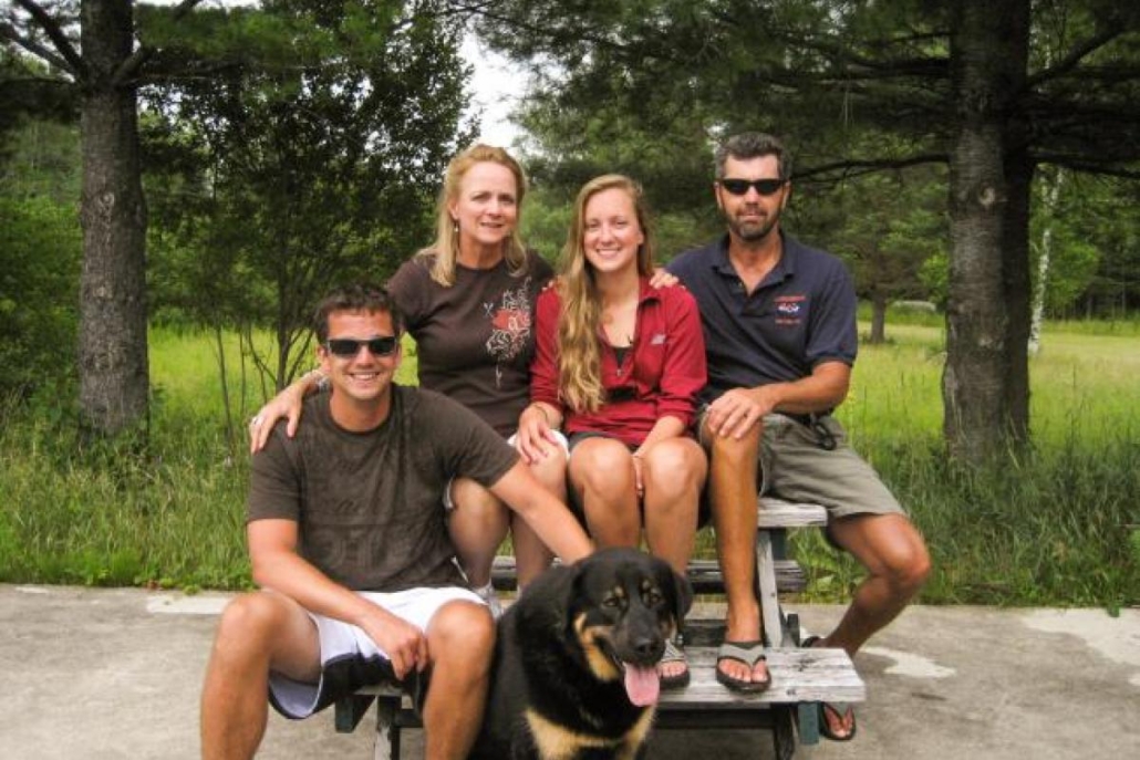 The Rafferty family sitting together on top of a picnic table with their dog at Adirondac Rafting Company